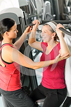 Personal trainer assist senior woman at gym