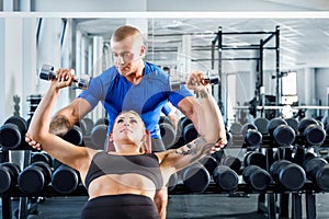 Personal trainer assisting while exercises at the gym.