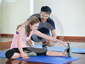 Personal trainer with attractive asian woman doing exercis
