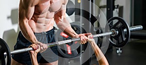 Personal trainer with barbell flexing muscles in gym