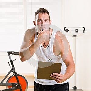 Personal trainer blowing whistle in health club