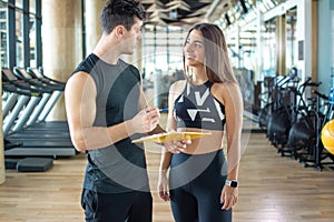 Personal trainer and client discussing her progress at the gym.
