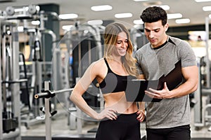 Personal trainer and client looking at her progress at the gym