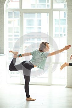 Personal trainer corrects his female client while doing yoga pose in studio.