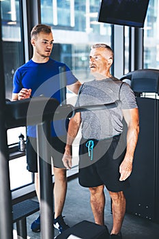 Personal trainer giving instructions to older man at the gym