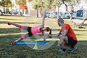 Personal trainer guiding a woman doing exercises outdoors