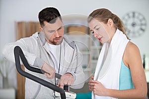 personal trainer guiding woman on exercise machine