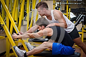 Personal trainer helping client in gym