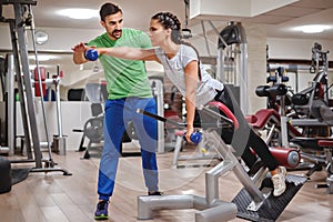 Personal trainer helping girl to train shoulders