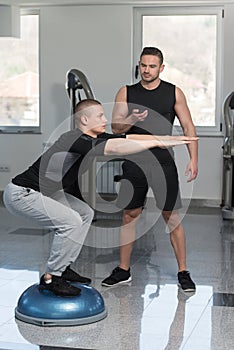 Personal Trainer Helping Man On Bosu Balance Ball