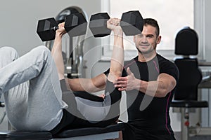 Personal Trainer Helping Man On Chest Exercise
