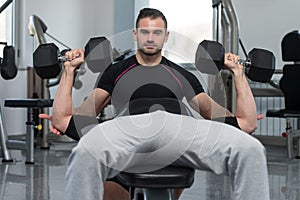 Personal Trainer Helping Man On Chest Exercise