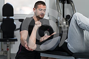 Personal Trainer Helping Man On Chest Exercise