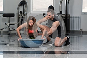 Personal Trainer Helping Woman On Bosu Push Ups