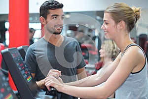 personal trainer helping woman in gym