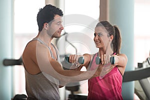 Personal Trainer Helping Woman On Shoulder Exercise