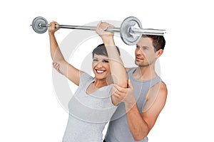 Personal trainer helping woman with weight lifting bar photo