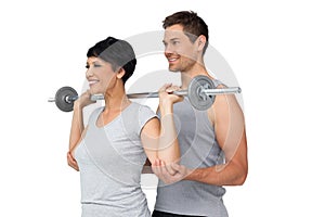 Personal trainer helping woman with weight lifting bar