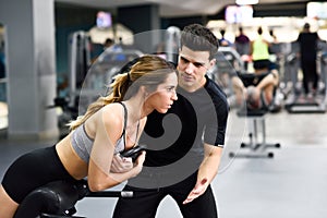 Personal trainer helping young woman lift weights