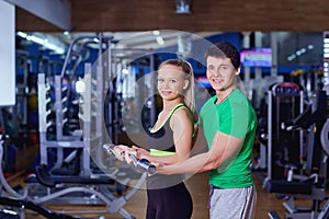 Personal trainer helps a girl lifting weights in the gym