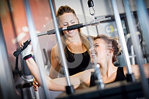 Personal trainer helps with gym equipment workout.