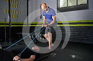 Personal trainer holding resistance bands. Mature man does bicep curl