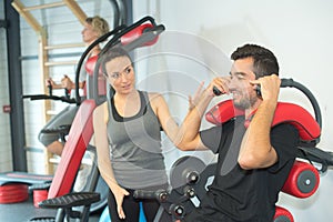 Personal trainer instructing trainee in gym