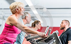 Personal trainer instructs senior woman about spinning at the gy