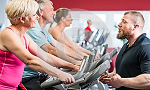 Personal trainer instructs senior woman about spinning at the gy
