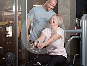 Personal trainer man helps middle aged woman