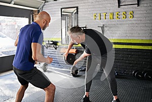 Personal trainer motivating senior man while wood choppers exercise