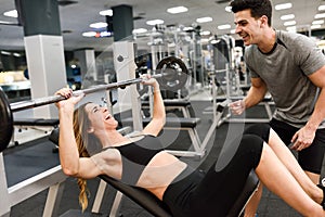 Personal trainer helping a young woman lift weights