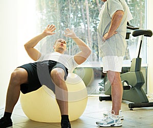 Personal trainer and senior man in fitness club