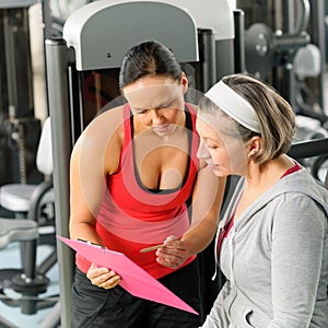 Personal trainer with senior woman at gym