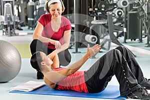 Personal trainer show abdominal exercise on mat