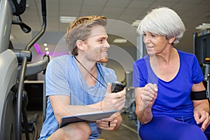 personal trainer showing stopwatch time to elderly woman