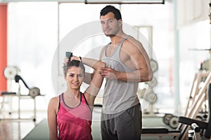 Gym Coach Helping Woman On Triceps Exercise