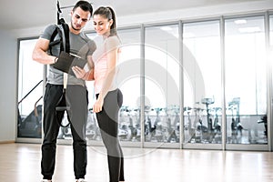 Personal trainer with suspension showing results to client.