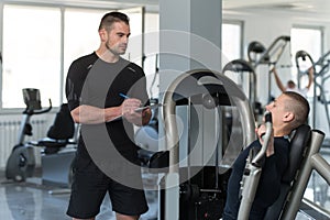 Personal Trainer Takes Notes While Man Exercising Chest