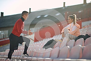 Personal trainer talking, explaining, with a smile and hand gesture to young adult female