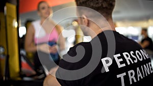 Personal trainer talking to female gym client after workout, sport club service