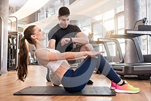 Personal trainer timing young fit woman during isometric exercis