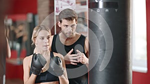 Personal trainer training woman at boxing workout in sport club.