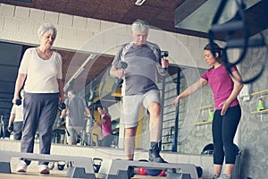 Personal trainer working exercise with senior couple.