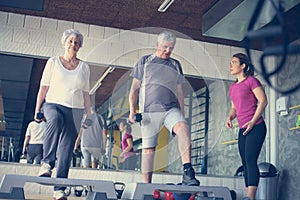 Personal trainer working exercise with senior couple.