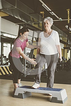 Personal trainer working exercise with senior woman.
