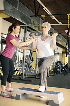 Personal trainer working exercise with senior woman in the gym.