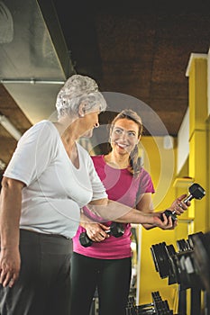 Personal trainer working exercise with senior woman in the gym.
