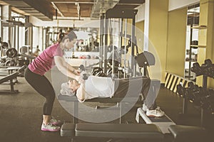 Trainer working exercise with senior woman in the gym.