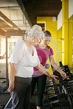 Trainer working exercise with senior woman in the gym.